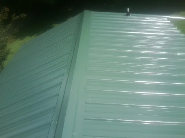 New green metal panels meeting at the ridge of a roof — Flat Roof Repair work by our crew in Nodaway