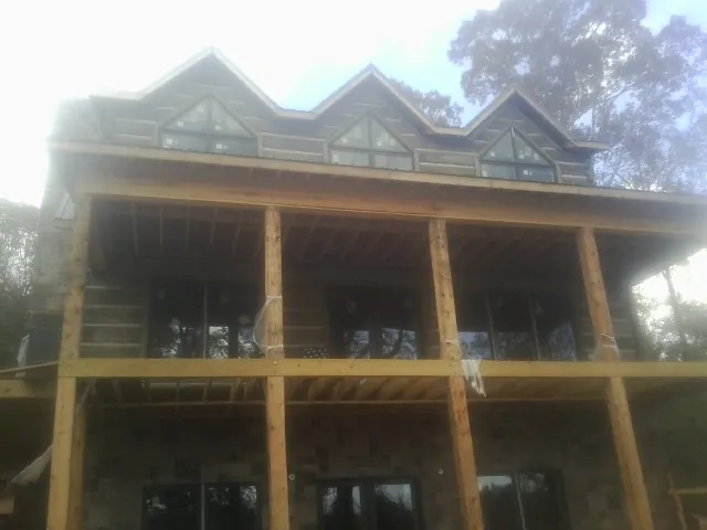 Dormers and porch framing on a large log home under construction — Roof Coating work by our crew in Nodaway
