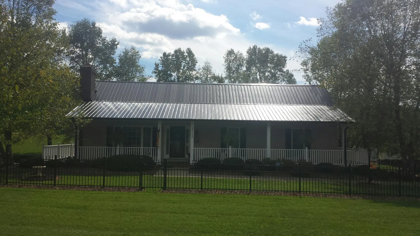 Gray metal roof on a brick ranch with a full width front porch — Gutter Guard Installation work by our crew in Nodaway