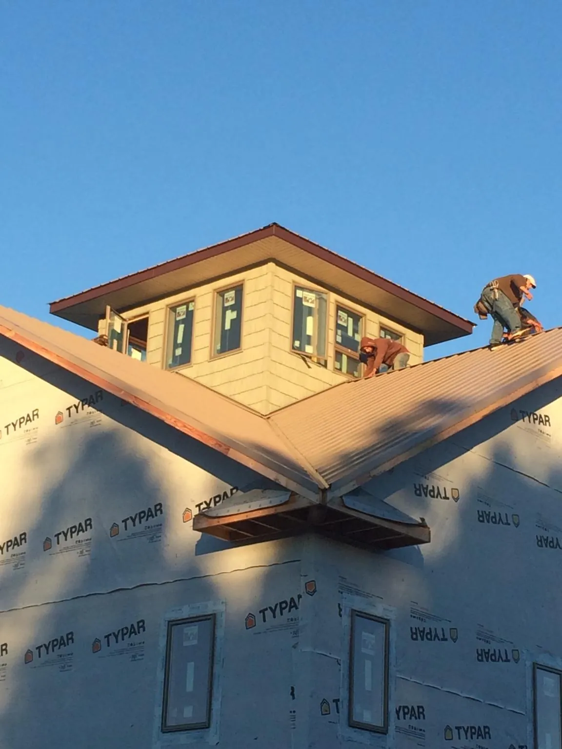 Roofers working around a rooftop cupola on a new metal roof at sunset — Roof Waterproofing in Nodaway by Roofing Brothers